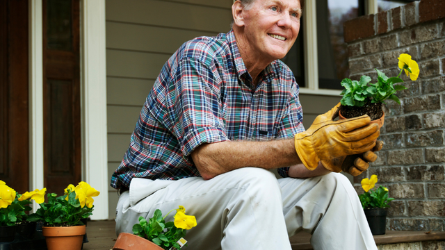 Man holding plant while sitting on porch steps